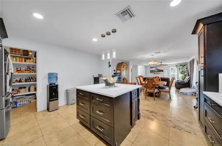 Kitchen with dark brown cabinetry, freestanding refrigerator, pendant lighting, a kitchen island, and recessed lighting