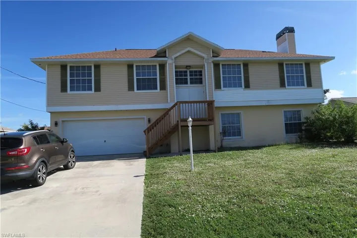 View of front of home with a chimney, concrete driveway, a front lawn, an attached garage, and stucco siding