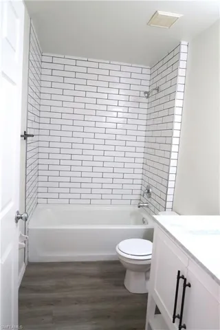 Full bathroom with washtub / shower combination, vanity, and dark wood finished floors