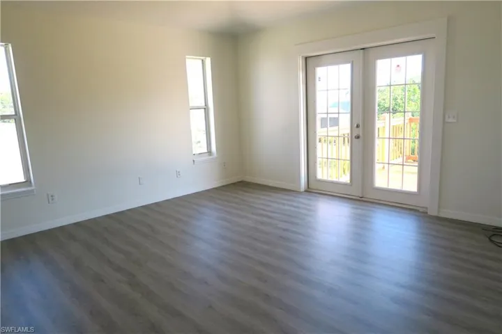 Unfurnished room featuring french doors, dark wood-style flooring, and plenty of natural light