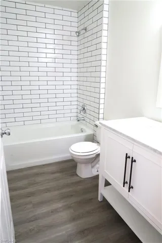 Bathroom featuring vanity, bathtub / shower combination, and dark wood-style flooring