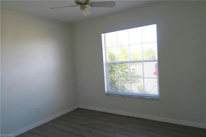 Empty room with dark wood-type flooring and ceiling fan