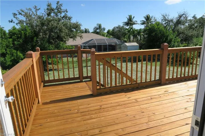 Wooden deck featuring a shed, a lawn, and glass enclosure