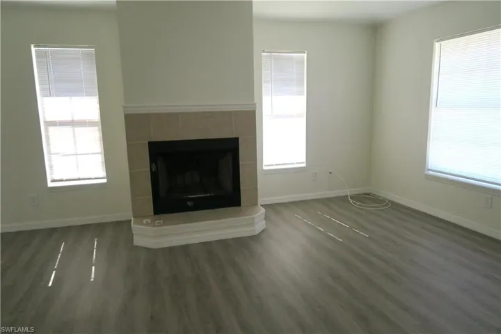 Unfurnished living room with a fireplace, dark wood-type flooring, and healthy amount of natural light