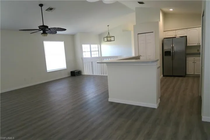 Kitchen featuring stainless steel refrigerator with ice dispenser, vaulted ceiling, open floor plan, ceiling fan, and pendant lighting