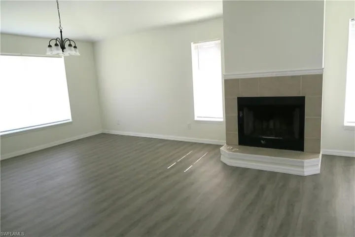 Unfurnished living room with a fireplace, dark wood finished floors, and a chandelier