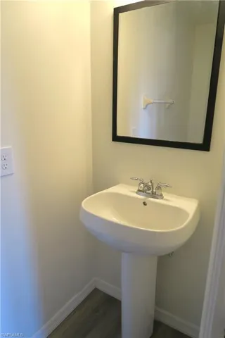 Bathroom featuring baseboards and dark wood-style floors