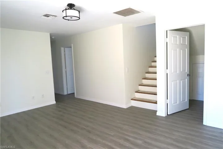Unfurnished room featuring dark wood-type flooring and stairway