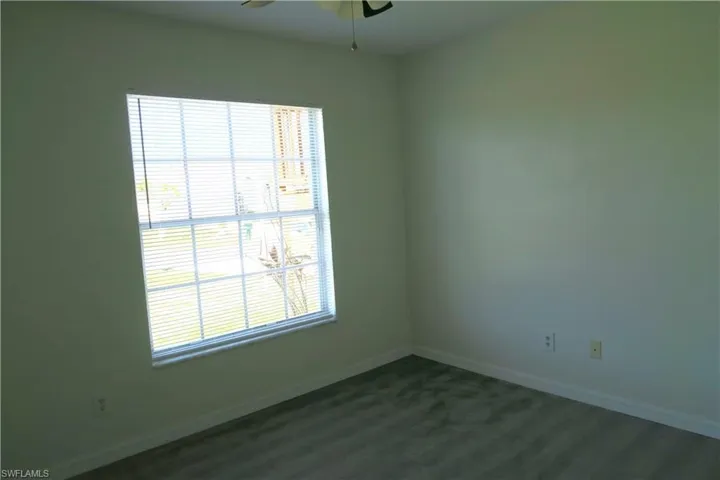 Empty room with ceiling fan and dark colored carpet