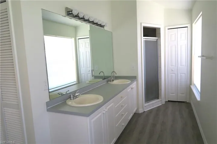 Full bathroom with a closet, double vanity, and a shower stall