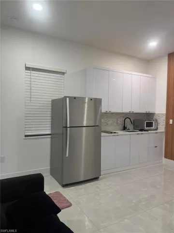 Kitchen with freestanding refrigerator, white cabinetry, tasteful backsplash, modern cabinets, and recessed lighting