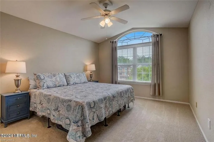 Carpeted bedroom with ceiling fan and vaulted ceiling
