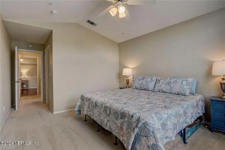 Bedroom with carpet floors, ceiling fan, and vaulted ceiling