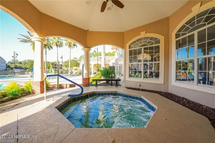 View of swimming pool with ceiling fan and a hot tub