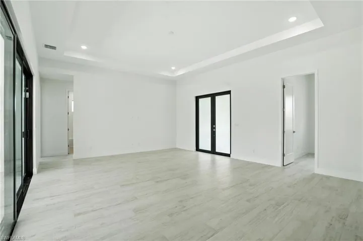 Unfurnished room with a tray ceiling, recessed lighting, and light wood-type flooring