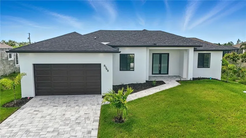View of front of home with a front lawn, stucco siding, and decorative driveway