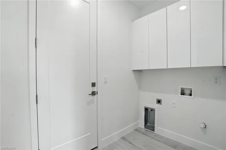 Laundry room with cabinet space, hookup for an electric dryer, hookup for a washing machine, and light wood-type flooring