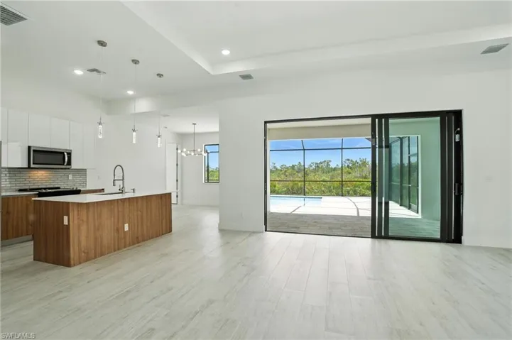 Kitchen with open floor plan, white cabinets, modern cabinets, tasteful backsplash, and a kitchen island with sink