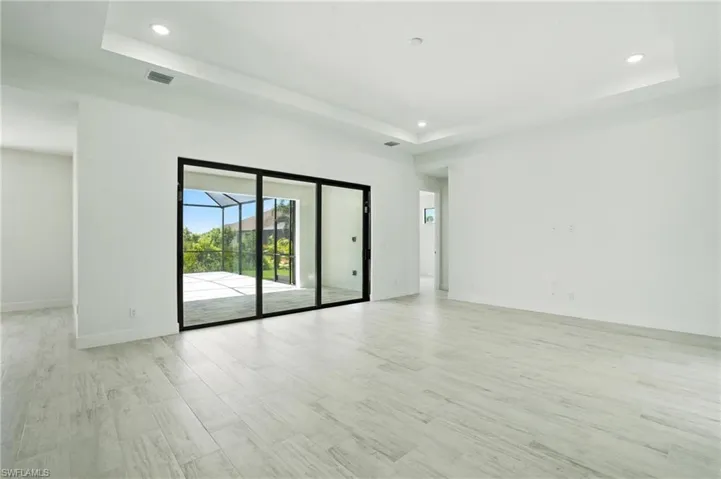 Empty room featuring a raised ceiling, recessed lighting, and light wood-type flooring