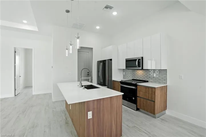 Kitchen featuring appliances with stainless steel finishes, a center island with sink, white cabinetry, modern cabinets, and recessed lighting