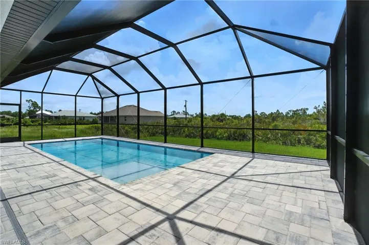 Outdoor pool featuring a patio area and glass enclosure