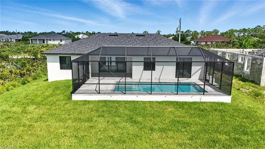 Back of house with a patio, stucco siding, glass enclosure, and a lawn