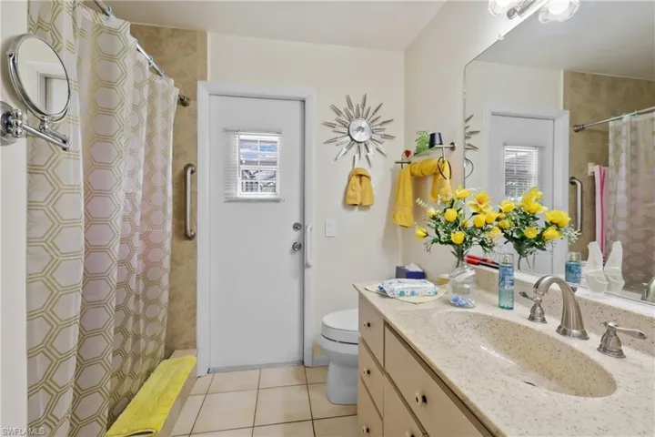 Bathroom featuring tile patterned flooring, vanity, toilet, and curtained shower