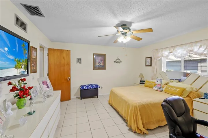 Bedroom featuring ceiling fan, light tile patterned flooring, and a textured ceiling