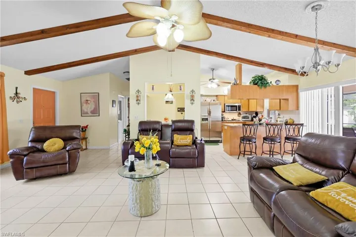 Tiled living room with a notable chandelier and vaulted ceiling with beams