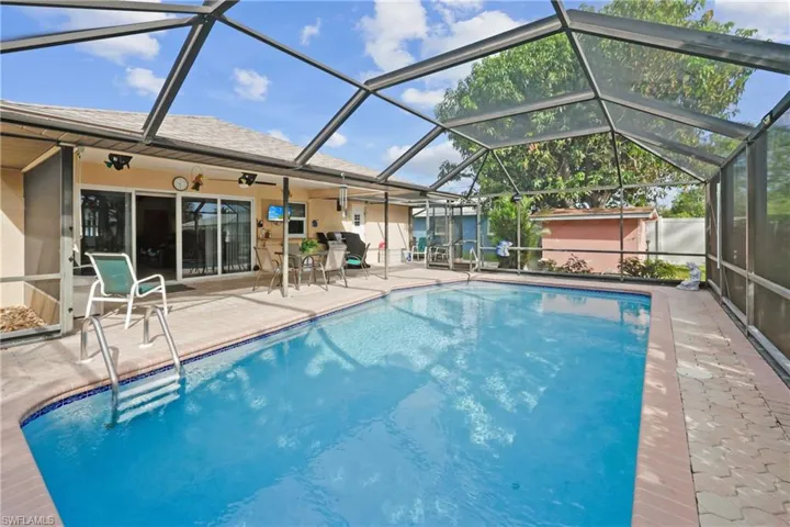 View of pool featuring glass enclosure, ceiling fan, and a patio