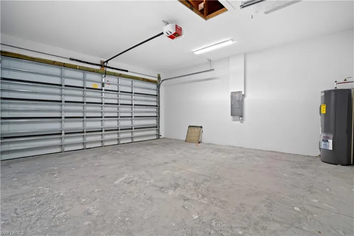 Garage with water heater, electric panel, and a garage door opener