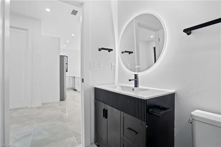 Half bathroom with vanity, recessed lighting, and light marble finish floors