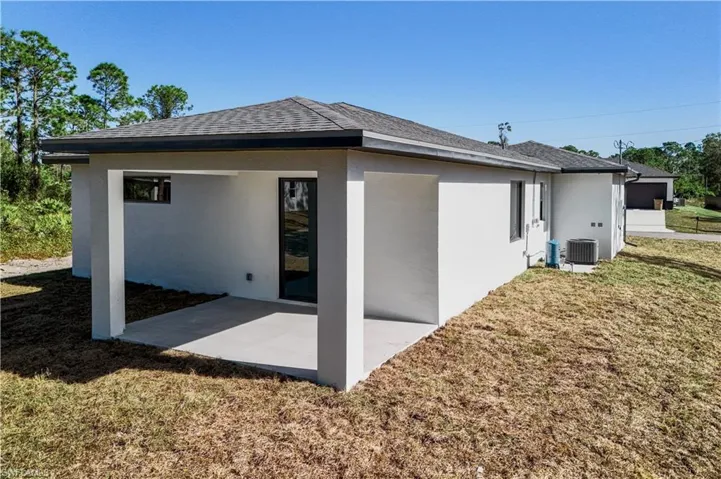 Rear view of property with a lawn and stucco siding