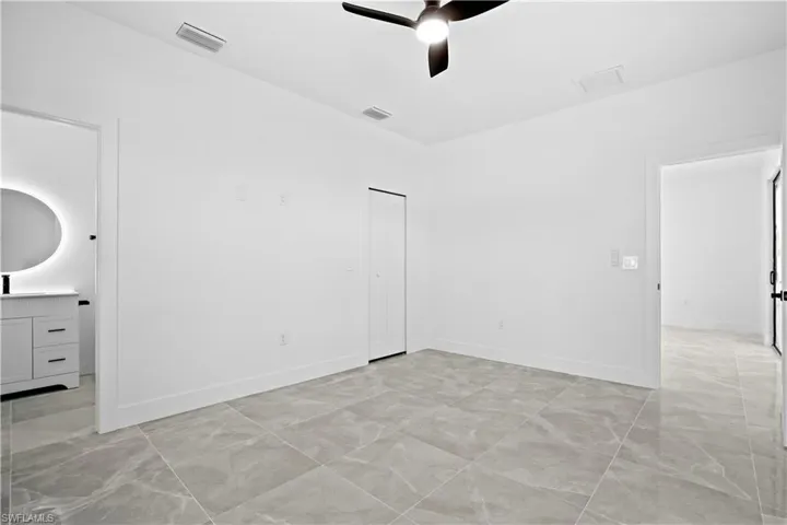Unfurnished bedroom with a ceiling fan, a closet, and ensuite bathroom