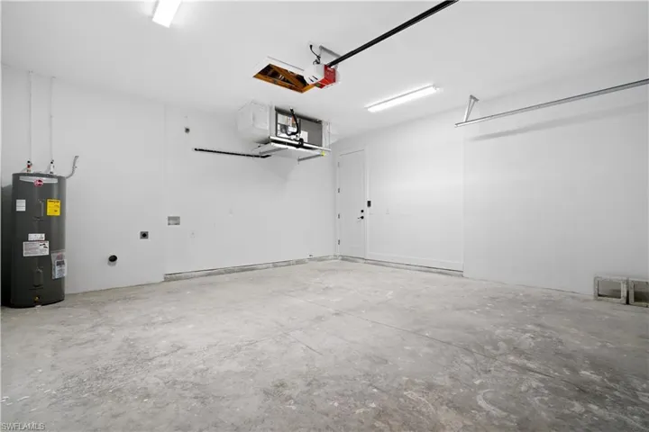 Garage featuring electric water heater and a garage door opener