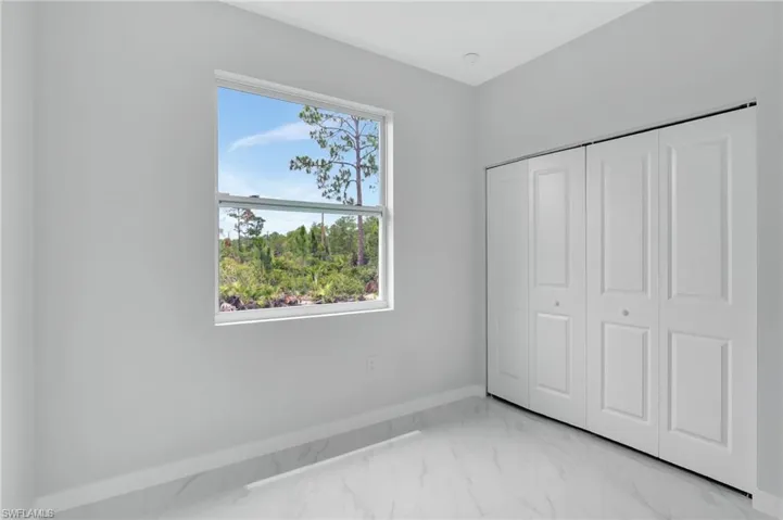 Unfurnished bedroom with baseboards, light marble finish floors, and a closet