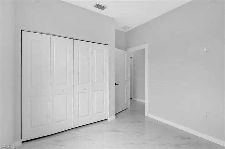 Unfurnished bedroom with light marble finish flooring, baseboards, and a closet