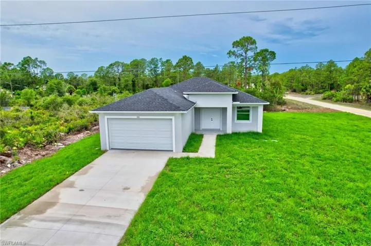 View of front of property with roof with shingles, driveway, a front yard, a garage, and stucco siding