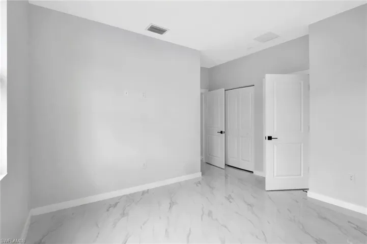 Unfurnished bedroom featuring baseboards, marble finish flooring, and a closet