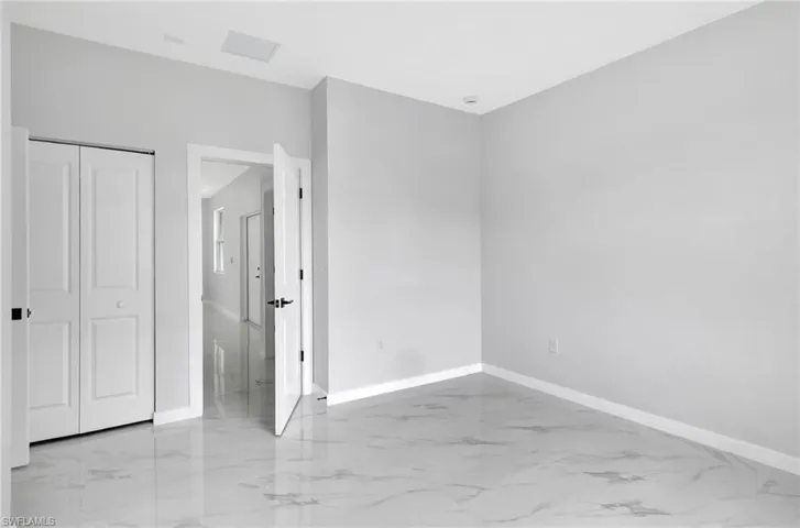 Unfurnished bedroom with baseboards, light marble finish flooring, and a closet