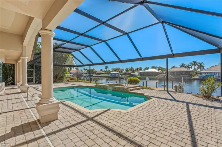 Integrated pool / hot tub featuring a sunroom, a patio, glass enclosure, a residential view, and a dock