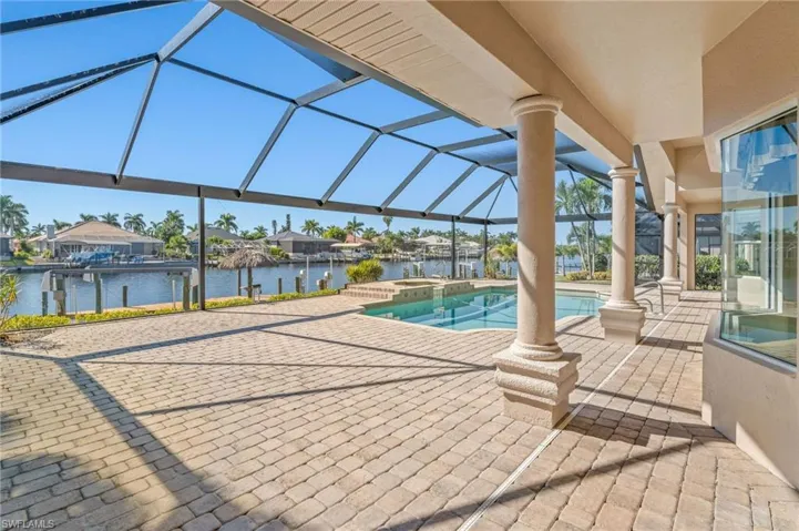 Integrated pool / hot tub with a sunroom, a patio area, glass enclosure, a residential view, and a water view