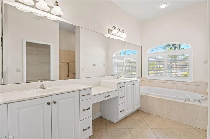 Full bathroom featuring a stall shower, double vanity, a garden tub, and light tile patterned floors