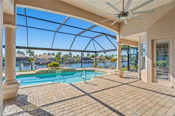 Relaxing pool / spa featuring a sunroom, a patio area, glass enclosure, a residential view, and a water view