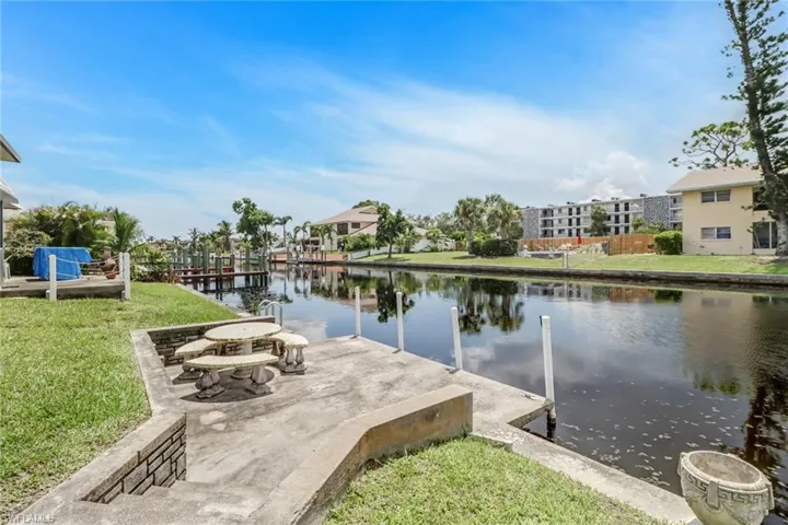 View of dock featuring a water view, a patio area, an outdoor fire pit, and a yard