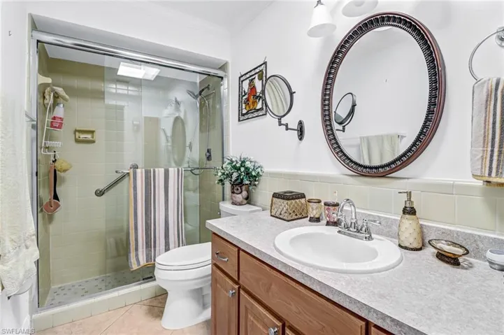 Bathroom featuring vanity, toilet, a shower with shower door, tile patterned flooring, and decorative backsplash