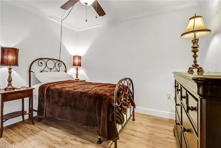 Bedroom featuring ceiling fan, light hardwood / wood-style flooring, and crown molding
