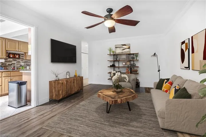 Living room with ornamental molding, ceiling fan, and dark hardwood / wood-style flooring