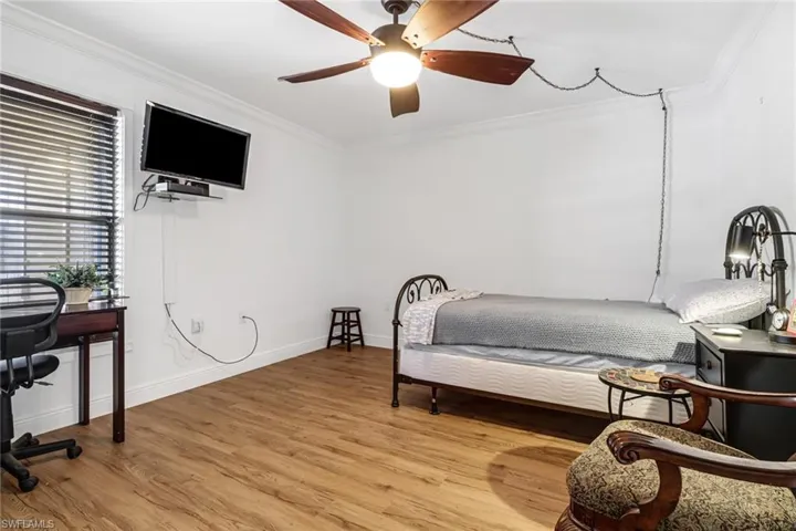 Bedroom with light hardwood / wood-style floors, ceiling fan, and crown molding