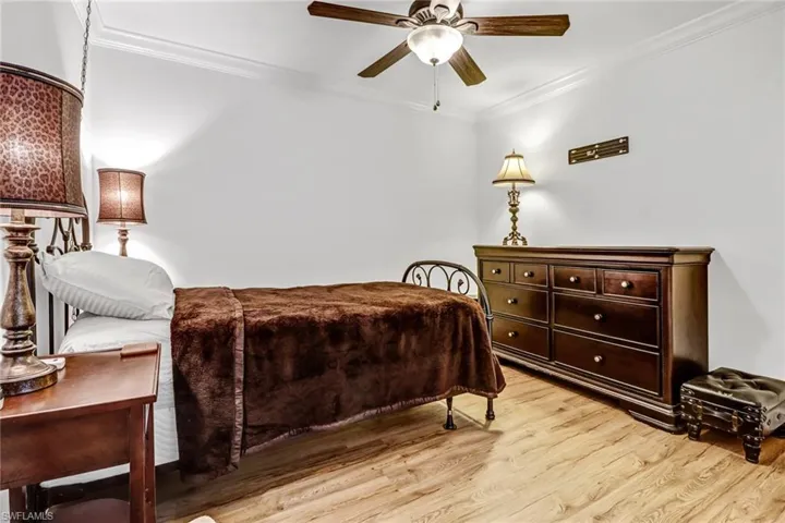 Bedroom featuring light hardwood / wood-style flooring, ceiling fan, and crown molding